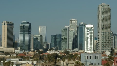 An afternoon view of city high rises buildings with some brown tiles residential homes in the front, a 4K, 24P video clip, Tel Aviv, Israel.