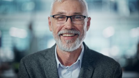 Portrait of Successful Middle Aged Bearded Man Looking at Camera and Smiling. Handsome Senior Businessman Wearing Jacket Rising Eyes, Having Fun. Slow Motion Medium Close-up Shot
