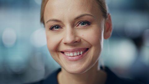 Portrait of Gorgeous Caucasian Woman with Deep Blue Eyes, Blonde Hair, Perfect Smile. Beautiful Girl Looks up at the Camera Happily. Abstract Bokeh out of Focus Background. Close-up Shot
