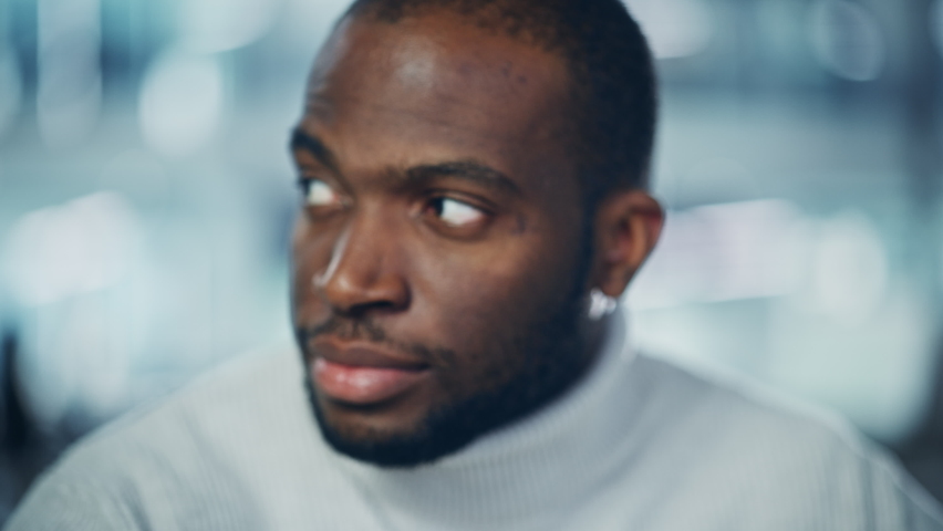 Close-up Portrait of Handsome Black Man with Deep Brown Eyes, Trimmed Beard, Wearing Stylish White Turtleneck, Winks and Shows Perfect Smile. Attractive Authentic Gentleman Turns, Looks at the Camera Royalty-Free Stock Footage #1081613993
