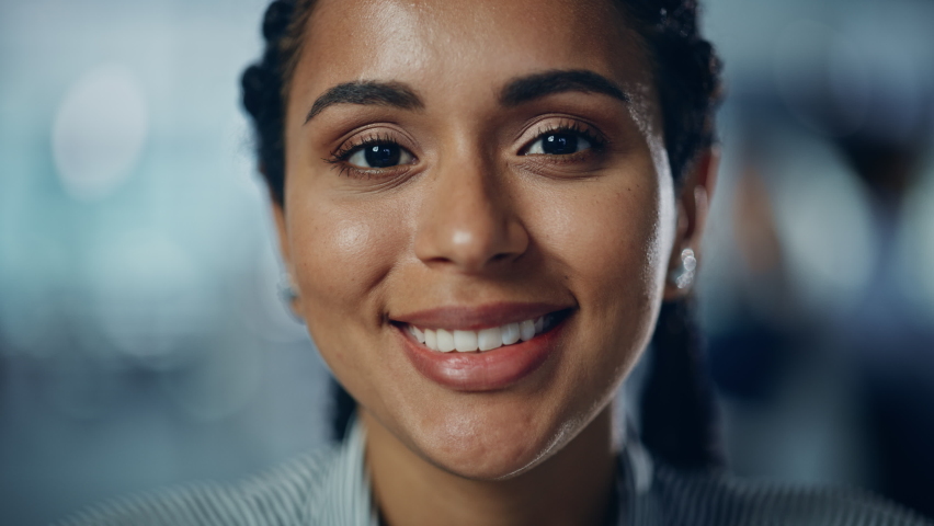 Portrait of Gorgeous Black Woman with Deep Brown Eyes, Braided Hair, Perfect Smile. Beautiful Girl Turns, Looks at the Camera with Kind Dreamy Gaze. Bokeh out of Focus Background. Close-up Slow Motion