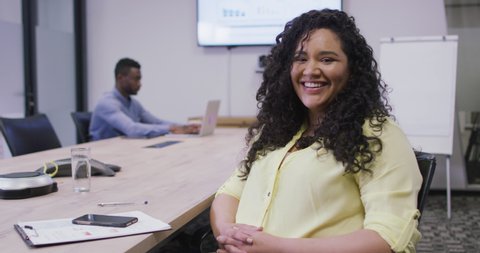 Portrait of smiling biracial businesswoman looking at camera in modern office. business and office workplace.