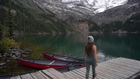 Lonely Woman Walking at Wooden Dock on Lake O'Hara, Yoho National Park, Canada. Glacial Water and Snow Capped Mountain Peaks, Full Frame - Powered by Shutterstock - Get 15% off with code: PIKWIZARD15
