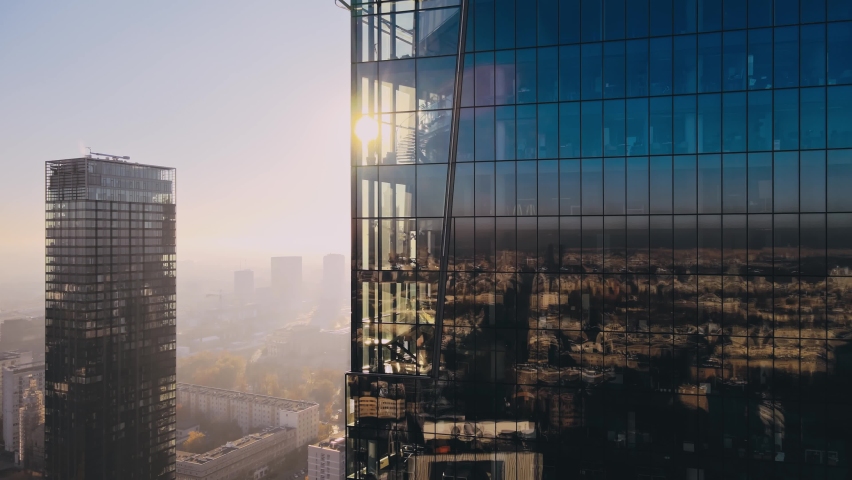 Modern business districtcity glass skyscrapers drone zoom in close to the buildings. Skyscraper in the big city top view during the sunrise when first sun rays are going through the glass windows. | Shutterstock HD Video #1081633133