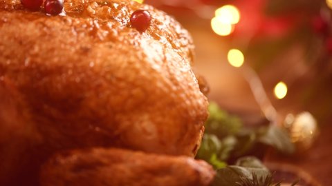 Christmas Roasted Chicken Dinner. Winter Holiday table served, decorated with candles. Delicious Steamed Roast chicken over wooden background with Christmas gifts, table setting. Dolly shot 4K UHD. 