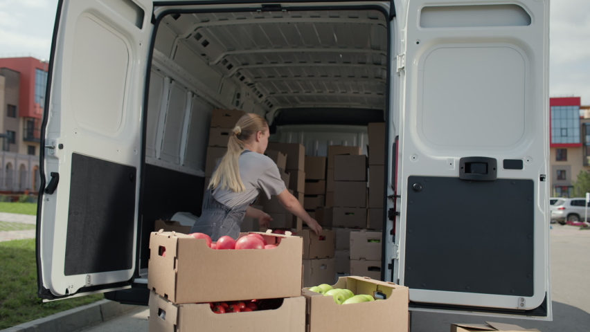 Harvest delivery to fruit market on food truck. Female worker carrying boxes of vegetables. Transport service to grocery trade from farm factory. Products supply on lorry van. Foodstuffs production Royalty-Free Stock Footage #1081639604