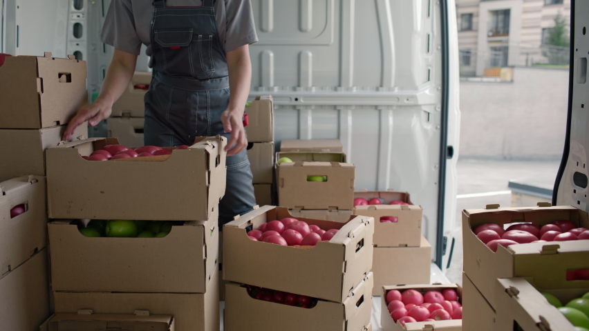 Harvest delivery to fruit market on food truck. Female worker carrying boxes of vegetables. Transport service to grocery trade from farm factory. Products supply on lorry van. Foodstuffs production | Shutterstock HD Video #1081639619