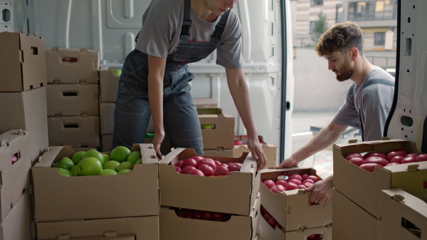 Harvest delivery to fruit market on food truck. Female worker carrying boxes of vegetables. Transport service to grocery trade from farm factory. Products supply on lorry van. Foodstuffs production Royalty-Free Stock Footage #1081639619