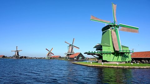Old windmills by the river in Holland. Traditional Windmill reflected in river canal in Netherlands. Oilmill in Zaanse Schans.