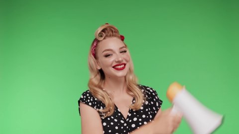 Smiling Young woman screaming in megaphone wearing black dress posing isolated on chroma key background in studio. Blond retro girl screaming in megaphone. Zoom out. Sale content, attention