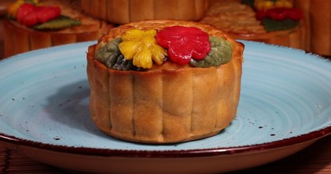 Mid autumn festive colorful flower decorated moon cake cutting with knife show layered inside on blue ceramic plate