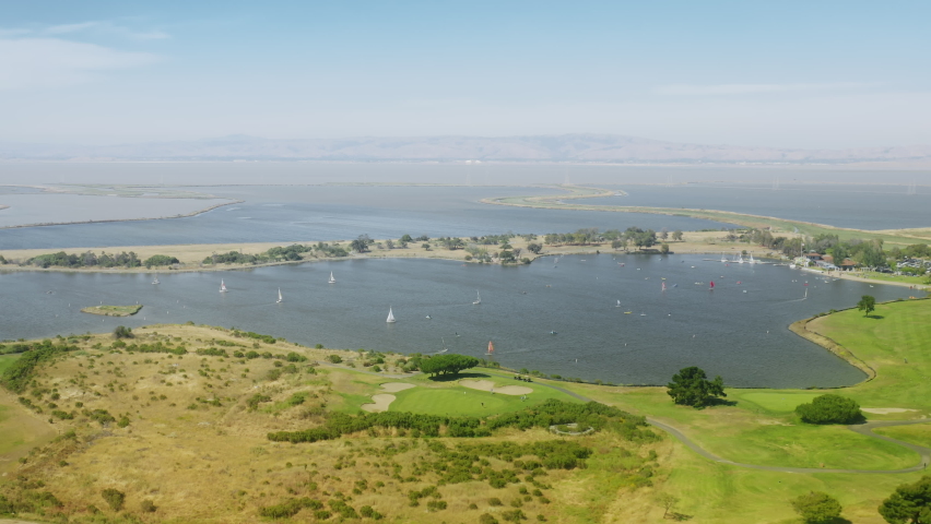 Aerial footage of beautiful boats, sailing in calm waters of the bay. Pristine natural landscape with lush green meadows and clear blue lakes as seen from above. High quality 4k footage