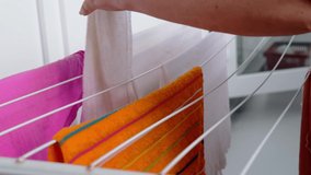 close-up of female hands of middle-aged woman hanging wet washed linen on wire dryer, home chores concept, selective focus at shallow depth of field