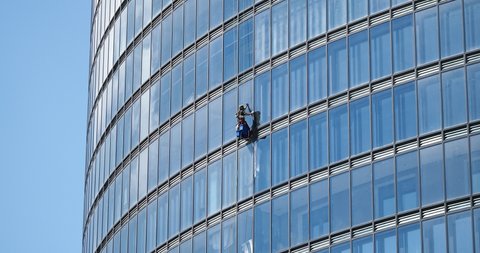 belarus,minsk,2021.industrial climber hanging on a rope washes the windows of a tall business building