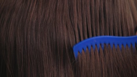haircare, comb moves along beautiful healthy long flowing brown hair close up, texture
