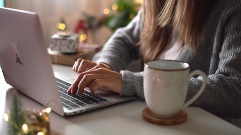 Woman hands with purse, credit card, gifts, coffee cup and laptop. Online shopping at Christmas holidays. Freelance girl woking from home office. Female typing at notebook computer. Christmas moments.
