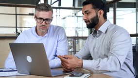 Two diverse business men analysts partners talking, working together, discussing data management using laptop computer. Indian manager consulting client with online technology at office meeting. - Powered by Shutterstock - Get 15% off with code: PIKWIZARD15