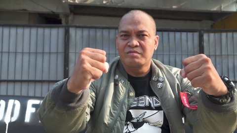 Indonesian skinhead man wearing a bomber jacket sitting on a black sofa by the roadside, Indonesia on October 31, 2021