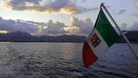 Italian flag waving in the wind at sunset at sea
