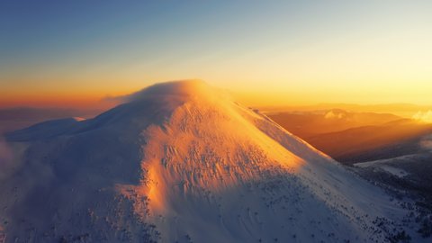 Epic Aerial Drone view of Winter high Mountain. Snow covered Top. Nature winter Landscape. Clouds above snowy mountain top 