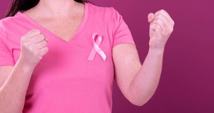 Video of breast cancer awareness text and logo over woman wearing pink cancer awareness ribbon. breast cancer positive awareness campaign concept.