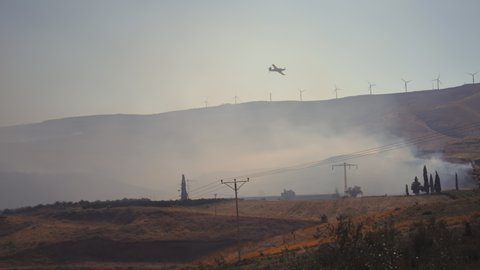 Rescue firefighting aircraft flying over the burning valley and village due to the heat wave. Global warming, climate change concept.
