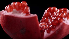 Closeup video of rotating pomegranate seeds on black background