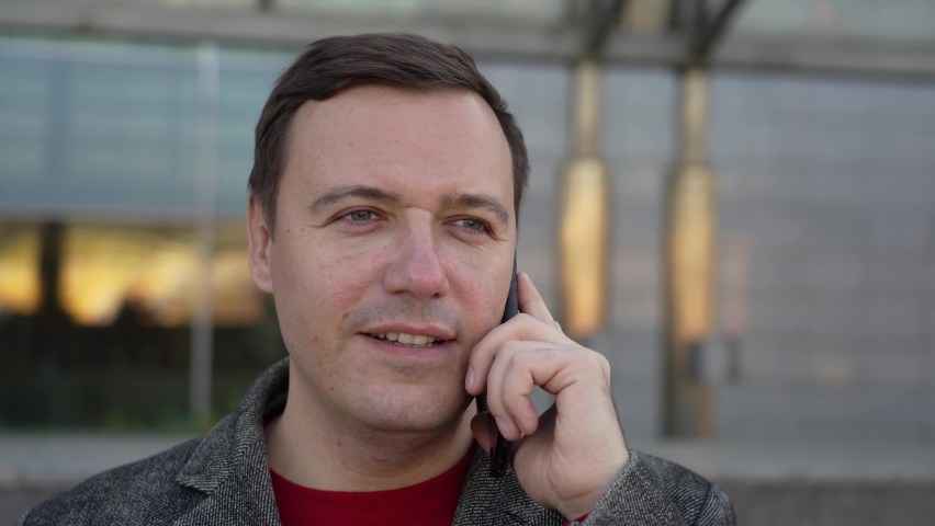 Millenial man holding smartphone moving forward