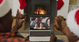 African american couple using laptop for christmas video call with smiling family on screen. christmas, festivity and communication technology.
