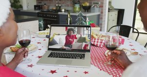 Smiling african american couple using laptop for christmas video call with woman on screen. christmas, festivity and communication technology.
