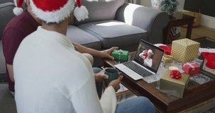 Biracial father and son using laptop for christmas video call with smiling woman on screen. christmas, festivity and communication technology.