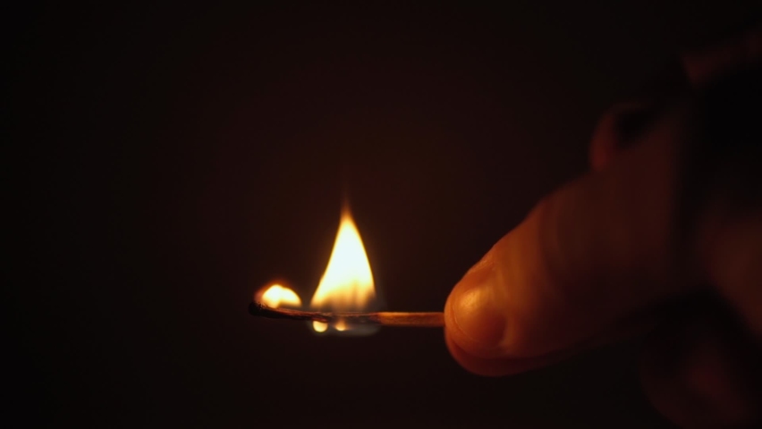 Close-up. A burning match in hand, illuminated by a flashing light of a fire flasher. Fires concept. | Shutterstock HD Video #1081689248
