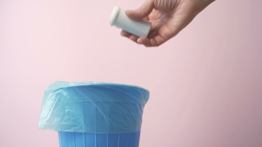 Hand throwing pills away, trash bin with pills and blisters inside, medecine in trashcan, pharmaceutical waste, expired medicines concept