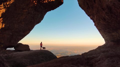 Amazing Sunset View Young man  and Dog hike in nature looking at the epic Landscape taking in the moment of friendship with pet animal silhouette in Montserrat, Catalonia