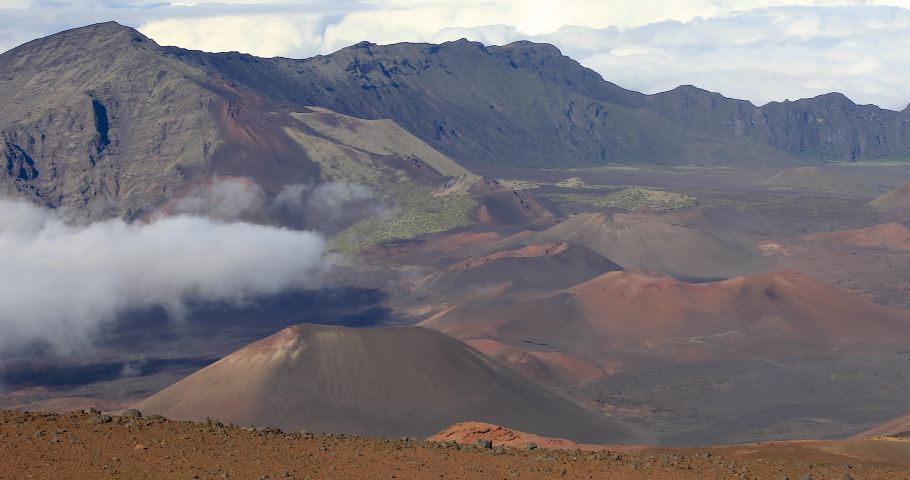 Slow left to right panning motion long lens view into the crater and puffy cloud cover at the top of  volcano summit crater at Haleakala National Park which is a massive shield volcano,Maui,Hawaii,USA Royalty-Free Stock Footage #1081698488
