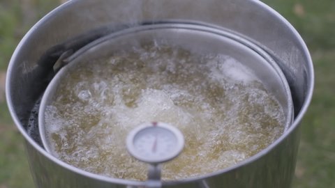 Person deep frying a turkey for Thanksgiving.  Lowering raw turkey into hot oil.