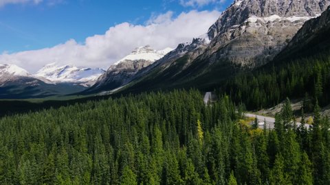 Ariel View of Road in Mountains and Forest with green Pine Woods in Banff National Park. Scenic view on Sunny day in Rocky Mountains in Canada. Road trip.