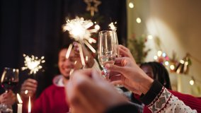 Best friends celebrating new year. International young people holding sparklers, sitting at dining table. Diverse students during christmas party at home, drinking champagne and laughing. - Powered by Shutterstock - Get 15% off with code: PIKWIZARD15