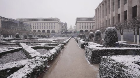 Slowlying forward in the beautiful Mont des Arts Gardens in Brussels, Belgium during snowfall - Pov tracking shot