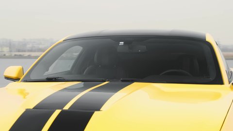 Yellow Ford Mustang with black stripes stands in a parking lot. Close-up of windshield and hood. Russia, Rostov-on-Don 23 Oct2021
