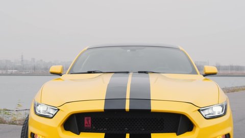 Yellow Ford Mustang with black stripes stands in a parking lot. Zooming in on the camera. Close-up. Russia, Rostov-on-Don 23 Oct2021

