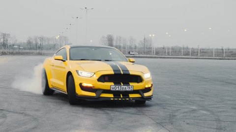 Yellow Ford Mustang with black stripes. Drift in the parking lot in the evening. Russia, Rostov-on-Don 23 Oct2021

