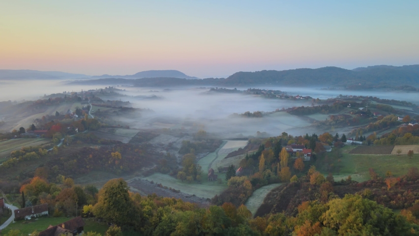 Drone flight over thick fog covering beautiful valley surrounded by mountains. Aerial over rural mountainous landscape