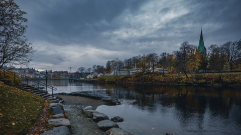 Gloomy Sky Over Nidelva River In Trondheim, Norway With View Of Nidaros Cathedral And A Man Feeding Ducks On The Riverside In Autumn. hyperlapse