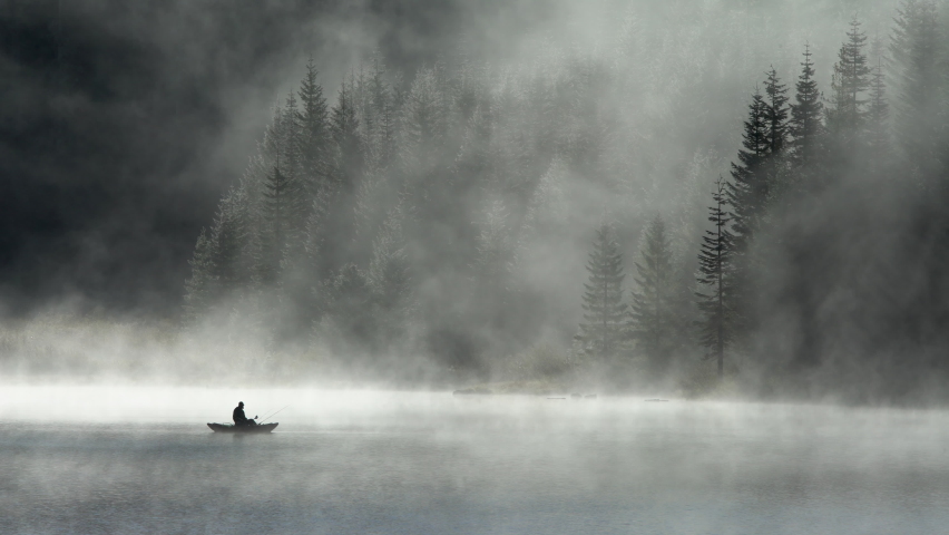 silhouette of man fishing on hemlock lake in the fog