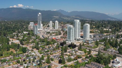 Aerial View Of Area Around Burquitlam Station In Coquitlam, British Columbia, Canada With Mountainous Landscape In Background. wide pullback