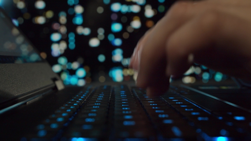 Hands of a young man working at a computer. The programmer is typing on a gaming laptop. Night city on the background. Business, coding and exchange concept. Royalty-Free Stock Footage #1081715756