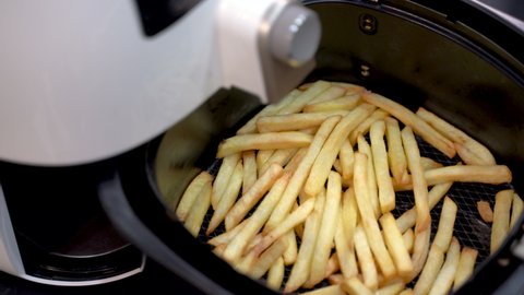 Air-frying delicious French fries cooked by airfryer at home. Healthy food for diet eating.