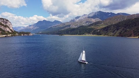 Aerial drone footage of a sailboat that sails on the Sils lake between Maloja and St Moritz in the Engadine valley in Graubunden Canton in Switzerland. 
