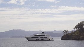 4k video footage of beautiful white yacht on blue sea water in scenic mountainous sunny landscape